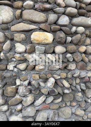 Struttura rustica delle pareti in pietra con agenti atmosferici naturali, ideale per sfondi, progetti architettonici e design vintage. Toni terrosi e motivi ruvidi Foto Stock