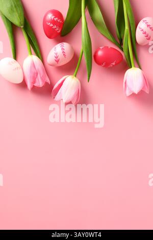 Modello banner verticale buona Pasqua. Fiori di tulipani piatti e uova di Pasqua colorate su sfondo rosa pastello. Foto Stock