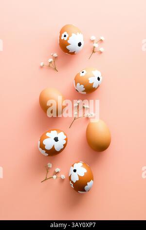 Buona Pasqua, composizione piatta creativa. Uova di Pasqua e fiori su sfondo rosa pastello. Foto Stock