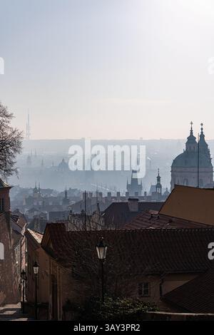 Vista panoramica di una mattina nebbiosa su un paesaggio urbano, con sagome di edifici storici e tetti che svaniscono all'orizzonte di Praga. La tranquillità della Foto Stock