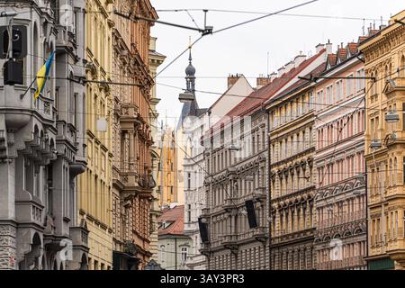Una vivace strada europea fiancheggiata da edifici storici colorati e complessi sotto il cielo nuvoloso di Praga. Con bandiere, architetture cha Foto Stock