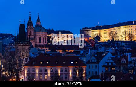 Una serena vista serale di Praga caratterizzata da edifici barocchi illuminati contro un cielo blu profondo. Questa immagine cattura la bellezza tranquilla della città A. Foto Stock