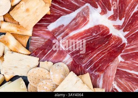 Un delizioso piatto con affettati sottili abbinati a una varietà di cracker croccanti. Perfetta per gli antipasti, questa sistemazione offre ricchi piatti Foto Stock