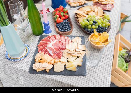 Un vivace assortimento di salumi con salumi, formaggi assortiti, frutta fresca come uva e bacche e cracker assortiti su un tavolo per Foto Stock