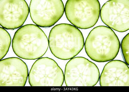 Un vivace motivo di fette di cetriolo disposte in modo ordinato mette in risalto la loro fresca texture verde su uno sfondo chiaro. La carne traslucida e i semi crescono Foto Stock