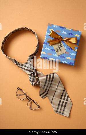 Vista dall'alto di un'elegante presentazione regalo per la festa del papà con cravatta a motivi geometrici, occhiali eleganti e una confezione regalo confezionata con un cartellino per la festa del papà, Foto Stock