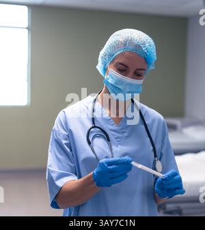 Giovane adulto donna medico professionale in piedi in sala esame clinica, con tampone in tubo trasparente Foto Stock