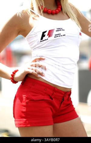 Le "ragazze della griglia" fanno parte degli sport motoristici internazionali tanto quanto il carburante ad alto numero di ottani, i tappi per le orecchie e gli incidenti ardenti. Prima di ogni gara, le ragazze della griglia prendono posizione dietro la linea di partenza, tenendo la bandiera nazionale della squadra e il numero del veicolo, o tenendo gli ombrelli sopra i piloti rivestiti in pelle per tenere il sole lontano da loro sull'asfalto bruciante. Inoltre, a quanto pare, passano un bel po' di tempo a stare in giro e a sembrare assurdamente caldi. A lungo, possano agitare. Nella foto: 30 maggio 2010 - Grid Girl Formula One World Championship, Rd 7, Gran Premio di Turchia, giornata di gara, Istanbul Park. Credito: © Sutt Foto Stock