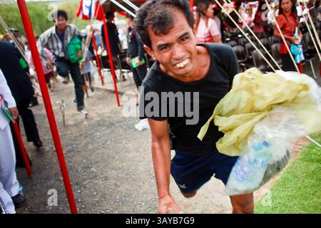 13 maggio 2010 - Bangkok, Thailandia - le persone si precipitano sul campo dopo la cerimonia reale di aratura per raccogliere semi di riso che sono stati benedetti dai sacerdoti Brahman. La cerimonia di aratura reale risale almeno al periodo Sukhothai (XIII e XIV secolo ca). L'evento è una cerimonia Brahman. In tempi antichi era per rappresentare le fortune agricole della prossima stagione di piantagione, benedire i campi e pregare per le piogge abbondanti. Ora si tratta più di un evento culturale che la monarchia thailandese, che presiede l'evento, usa per sottolineare l'importanza dell'agricoltura per la nazione. Tuttavia, la gente ancora Foto Stock
