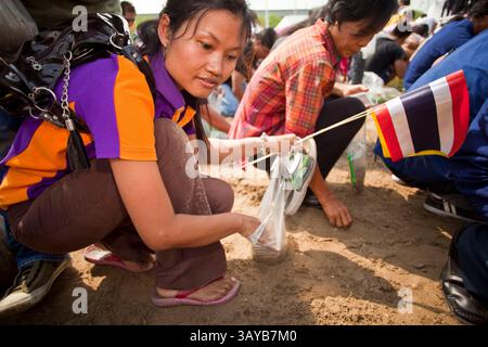 13 maggio 2010 - Bangkok, Thailandia - le persone cercano semi di riso che sono stati benedetti dai sacerdoti Brahman dopo la cerimonia reale di aratura. La cerimonia di aratura reale risale almeno al periodo Sukhothai (XIII e XIV secolo ca). L'evento è una cerimonia Brahman. In tempi antichi era per rappresentare le fortune agricole della prossima stagione di piantagione, benedire i campi e pregare per le piogge abbondanti. Ora si tratta più di un evento culturale che la monarchia thailandese, che presiede l'evento, usa per sottolineare l'importanza dell'agricoltura per la nazione. Tuttavia, la gente continua ad affluire ad esso per il reli Foto Stock