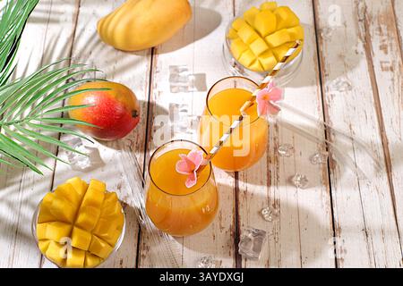 Concetto di festa estiva. Cocktail fatto in casa, succo di frutta o limonata con fette di mango e ghiaccio sul soleggiato tavolo da cucina. Ricetta per una bevanda dietetica estiva rinfrescante, DETO Foto Stock