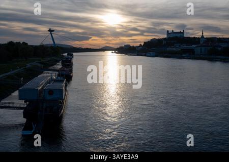 Panoramica generale del fiume Danubio a Bratislava durante il tramonto. Sullo sfondo si può ammirare la torre UFO, il ponte SNP, il castello di Bratislava e la cattedrale di San Martino. Foto Stock