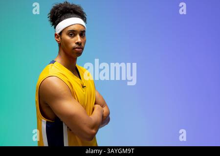 Giocatore di basket maschile che incrocia le braccia in studio, indossa maglia gialla e fascia, copia spazio Foto Stock