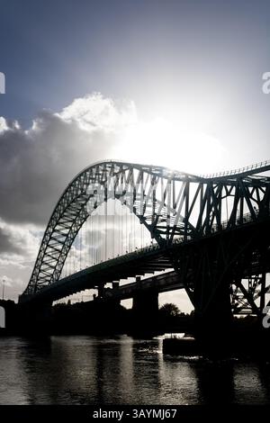Runcorn Bridge con sole basso dietro l'arco Foto Stock