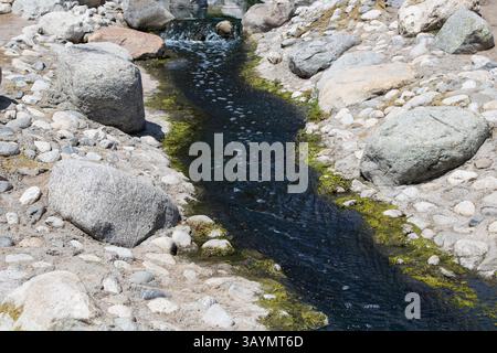 flusso blu profondo di acqua che scorre attraverso le rocce Foto Stock