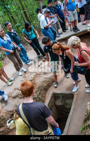 Visitatori dei tunnel di Cu chi che entrano nei tunnel Foto Stock