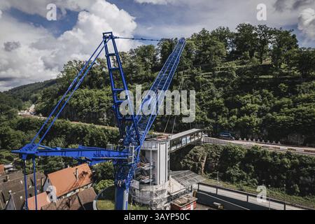 Calw, Baden-Wuerttemberg, Germania, Una gru erige un ponte sospeso in un'area boscosa sotto un cielo nuvoloso, l'Europa Foto Stock