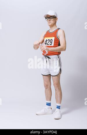 Nerd runner concentrato che beve acqua e si prepara per la gara, ritratto a figura intera, isolato su sfondo bianco Foto Stock