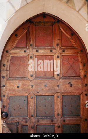 Una porta in legno lavorata con cura che mette in risalto l'artigianato medievale con eleganti dettagli in ferro Foto Stock