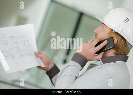 uomo al telefono che guarda i piani Foto Stock