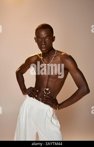 Giovane uomo afroamericano sicuro di sé in un'elegante veste e accessori sorprendenti in uno studio. Foto Stock