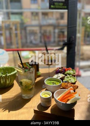 Cocktail rinfrescanti e vari antipasti sono serviti su un tavolo di legno in un ristorante a Pescara, in Italia, creando una piacevole esperienza aperitivo Foto Stock