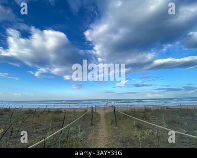Recinzione di corda che guida verso la spiaggia sabbiosa di Pineto, sotto un cielo nuvoloso in Abruzzo, Italia Foto Stock
