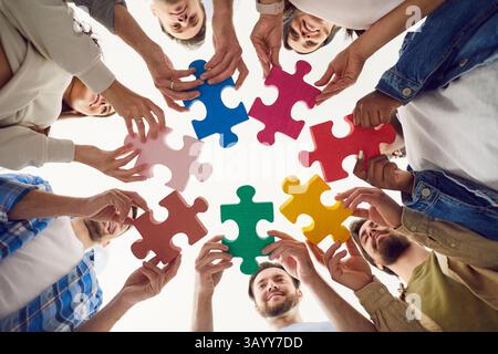 Puzzle, colleghi diversi che tengono pezzi colorati, trovano idee alla ricerca di soluzioni aziendali Foto Stock
