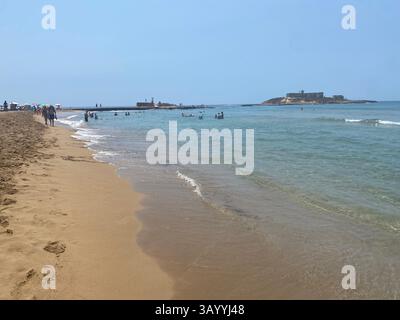 Turisti che nuotano e prendono il sole sulla spiaggia dell'Isola delle correnti a Portopalo di Capo Passero, una popolare destinazione estiva in Sicilia, Italia Foto Stock