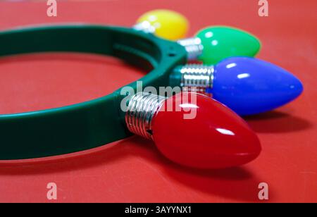 Fascia in plastica con quattro luci natalizie sedute su un tavolo rosso Foto Stock