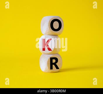 Obiettivi OKR e simbolo dei risultati chiave. Cubi in legno con parole obiettivi OKR e risultati chiave. Bellissimo sfondo giallo. Business e OKR. Foto Stock