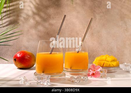 Concetto di festa estiva. Cocktail fatto in casa, succo di frutta o limonata con fette di mango e ghiaccio sul soleggiato tavolo da cucina. Ricetta per una bevanda dietetica estiva rinfrescante, DETO Foto Stock