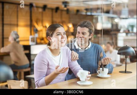 Uomo e donna allegri che si godono la data in un accogliente caffè Foto Stock