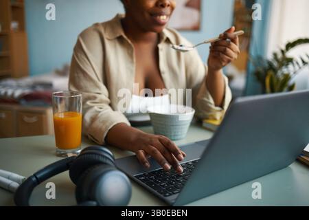 Donna sorridente che usa il notebook durante la colazione Foto Stock