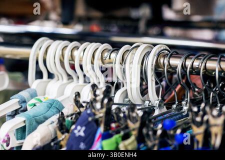 Un vasto assortimento di vestiti è elegantemente appeso su un appendiabiti in un vivace negozio al dettaglio, pronto per essere sfogliato dai clienti Foto Stock