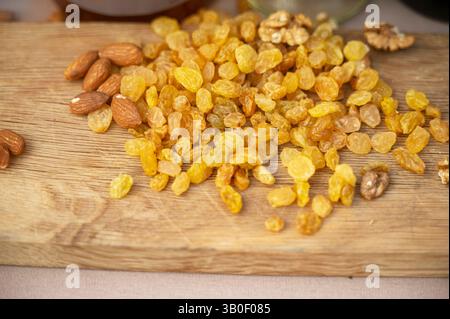 Uva passa, mandorle e noci di colore giallo chiaro si trovano su un asse di legno naturale Foto Stock