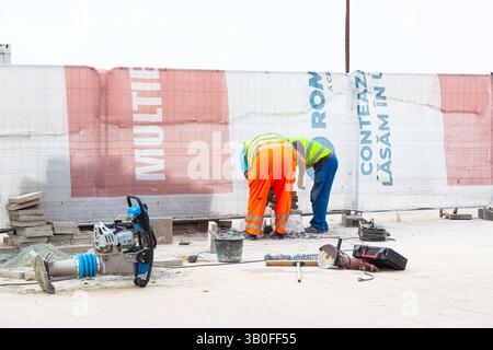 Lavori di riparazione stradale che coinvolgono persone, posa di nuove lastre di pavimentazione. Foto Stock