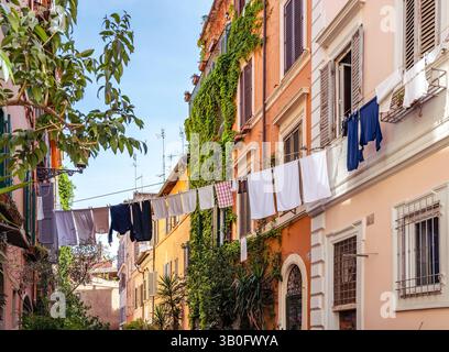 Vista pittoresca dell'area di Trastevere con edifici ricoperti di edera, case residenziali e lavanderia appesi su una linea in un affascinante vicolo di Roma, Italia Foto Stock