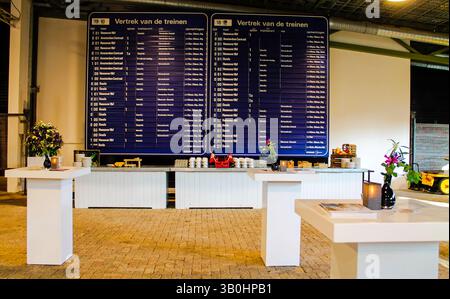 Disposizione degli eventi al coperto con tavoli e un grande banco di partenza del treno. Foto Stock