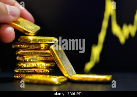 Primo piano con la mano che tiene una mano dorata fissa il grafico a candelabro. Contesto , concetto di fluttuazioni dei prezzi dell' oro. Foto Stock