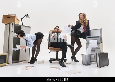 Donna che cerca all'interno dell'armadio mentre un'altra consegna i documenti al capo seduto in un ambiente d'ufficio surreale. Concetto di gerarchia del luogo di lavoro Foto Stock