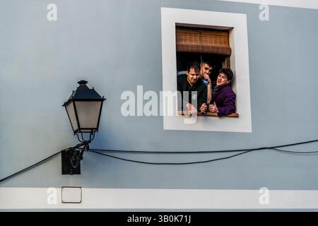 Tre giovani uomini guardano fuori da una finestra in Spagna.. Plaza Salvador, Cuenca, Castilla-la Mancha, Spagna Foto Stock