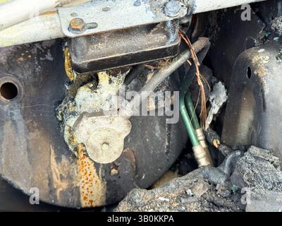 Valvola del compressore dell'aria condizionata bruciata da una vettura che presenta danni dovuti al calore, materiale di tenuta fuso, cablaggio in rame esposto e lin del refrigerante collegato Foto Stock