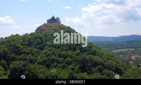 Vista aerea di un castello e fortezza medievale in cima alla collina di Füzér circondato da una lussureggiante foresta verde nella campagna ungherese. Antica roccaforte. Foto Stock