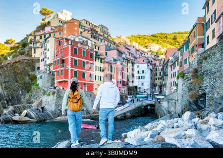 Mano nella mano, un paio di passeggiate lungo la costa rocciosa, affascinati dai colorati edifici di Riomaggiore. Un paio di uomini e donne in vacanza alle cinque Terre, Italia Foto Stock