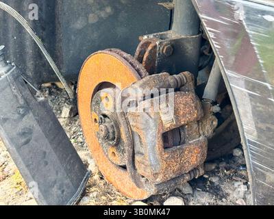 Pinza freni e disco arrugginiti di una vettura che mostra una forte corrosione sull'impianto frenante, con componenti delle sospensioni esposti e complessivo mozzo ruota. Foto Stock