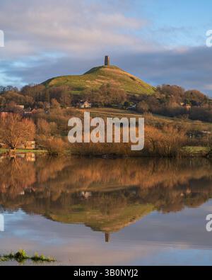 Una vista invernale, di prima mattina, del Glastonbury Tor, che si affaccia dal Cow Bridge attraverso i campi allagati del Lower Actis. Glastonbury, Somerset, Inghilterra, Regno Unito Foto Stock