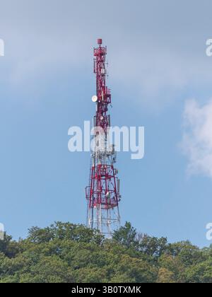 Array di antenne direzionali su una torre di comunicazione rossa e bianca contro il cielo. Foto Stock