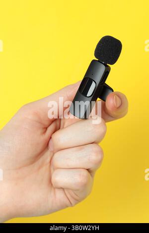 Donna con microfono lavalier su sfondo giallo, primo piano Foto Stock