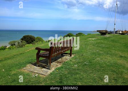 Una panchina in legno e un vecchio canone che si affaccia sul mare di Tankerton Foto Stock